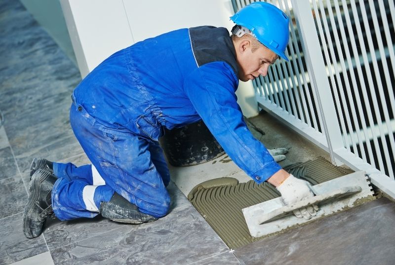 Commercial tilers spreading tiles adhesive for a commercial floor tiling job