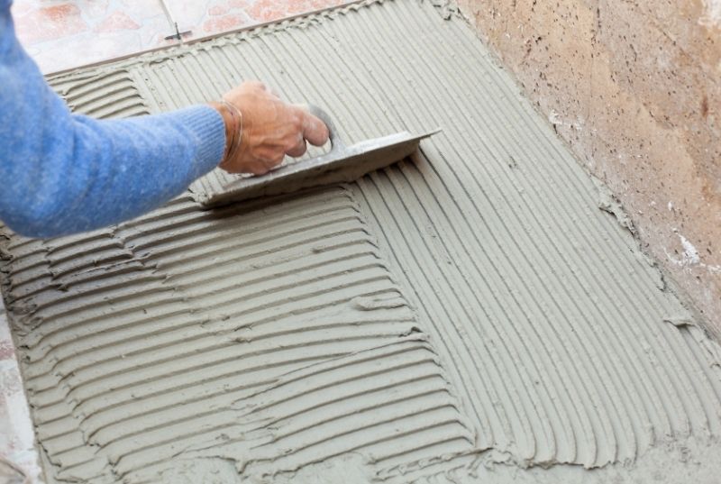 Tiler spreading tiles adhesive for an outdoor floor tiling installation