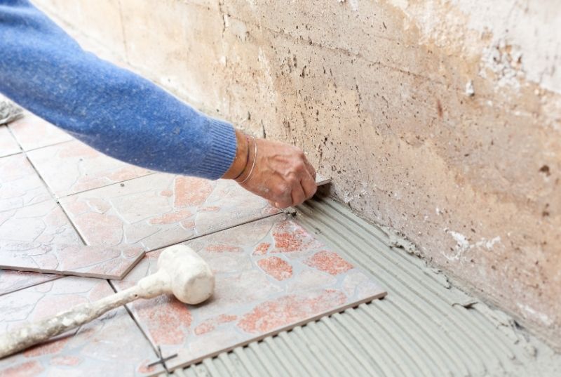 Tiler installing outdoor floor tiling using a mallet hammer