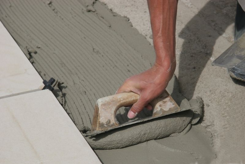 Person spreading tiles adhesive with a trowel tool for floor tiling