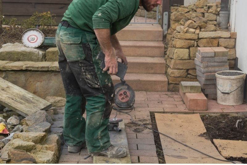Outdoor tiler about to use a grinder to cut flooring tiles for exterior patio