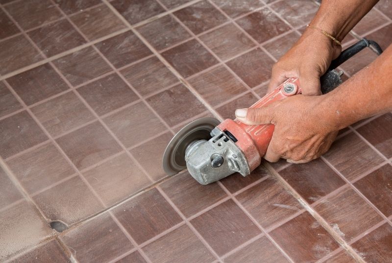 Person cutting an outdoor tiling floor for a balcony tile repair. He is using a grinder
