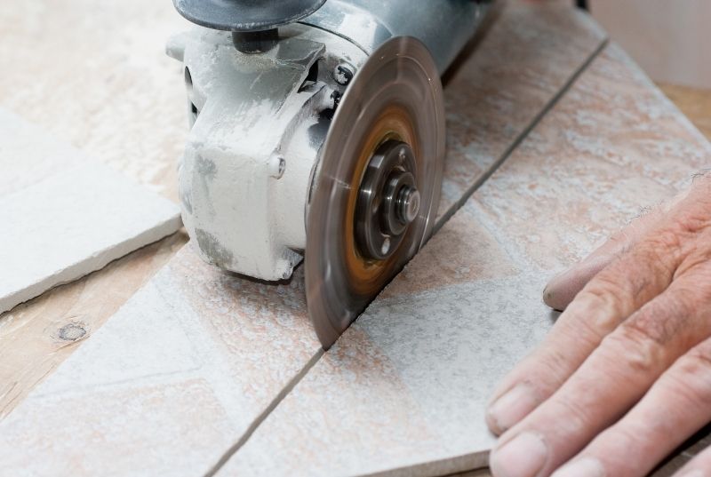 Person cutting a tile with a grinder