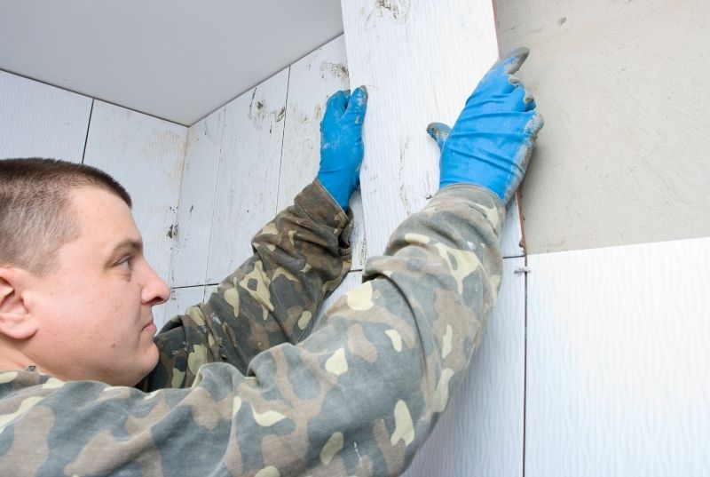 Tiler installing a wall tile in a bathroom