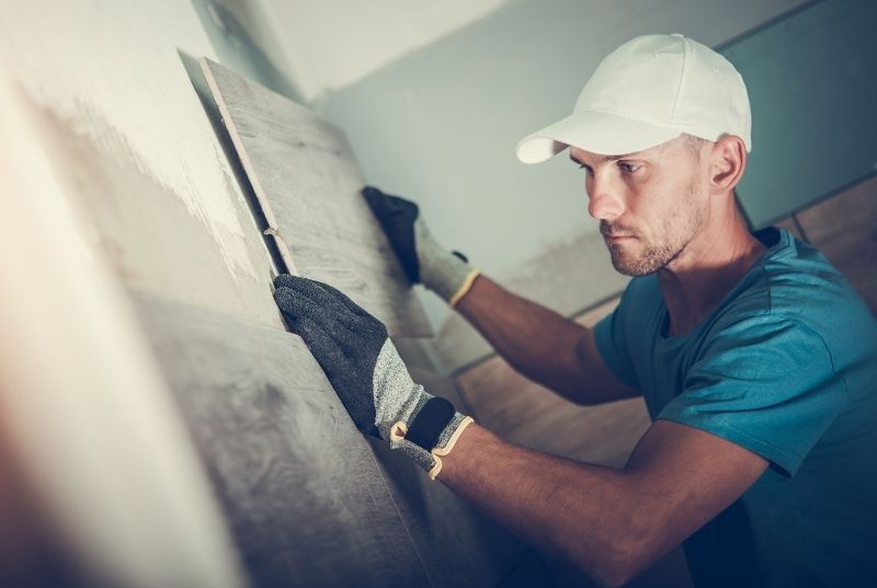 Tiler placing a wall tile during a commercial bathroom tiling job