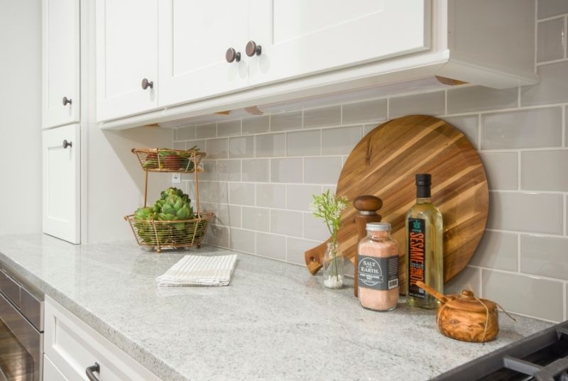 Kitchen bench with ceramic splashback tiling, spices and cookware on the benchtop