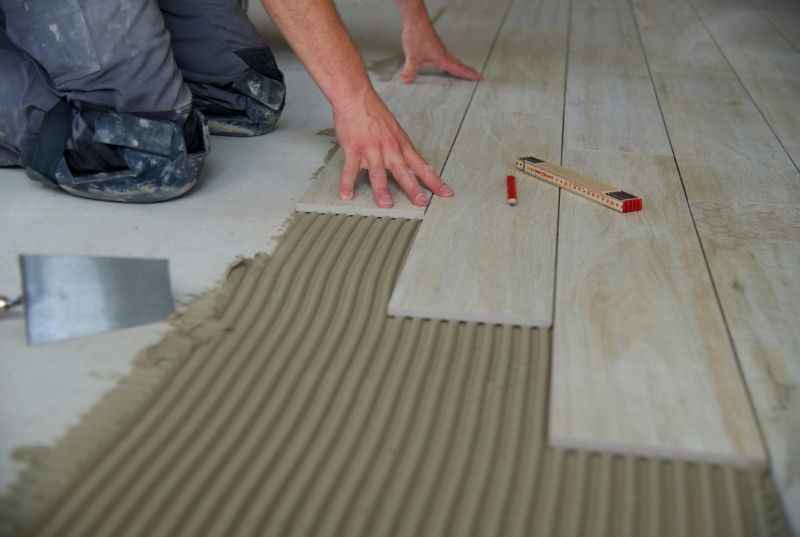 Tilers laying ceramic floor tiles during a residential installation