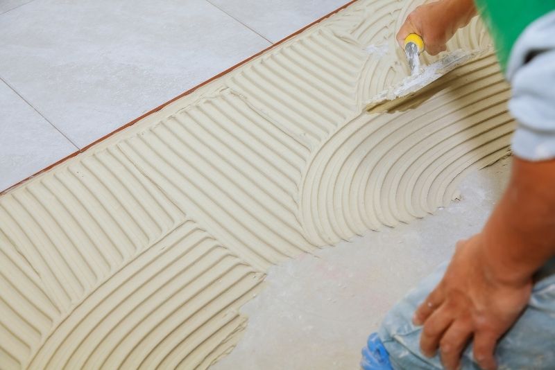 Tiler spreading tile adhesive on a flooring installation