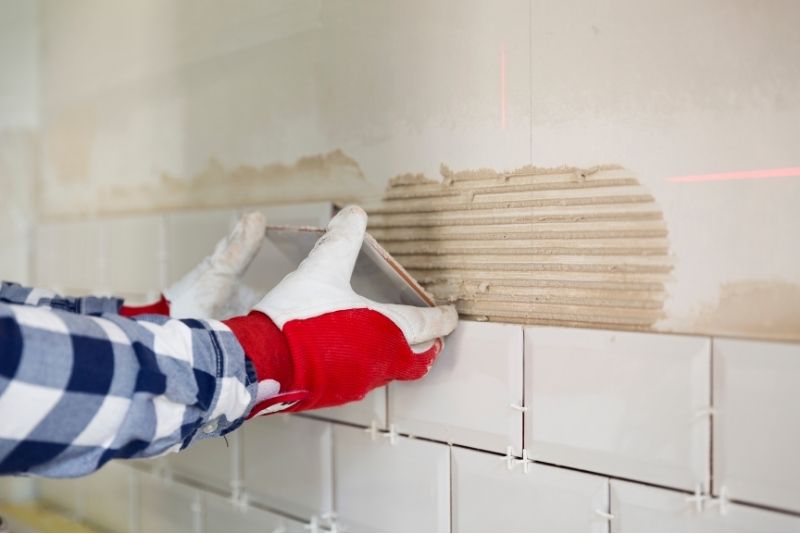 Tiler installing a kitchen splashback in white tiles