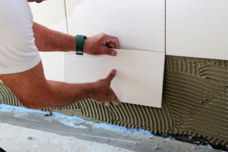 Tilers Woonona staff installing a ceramic tile on a bathroom wall