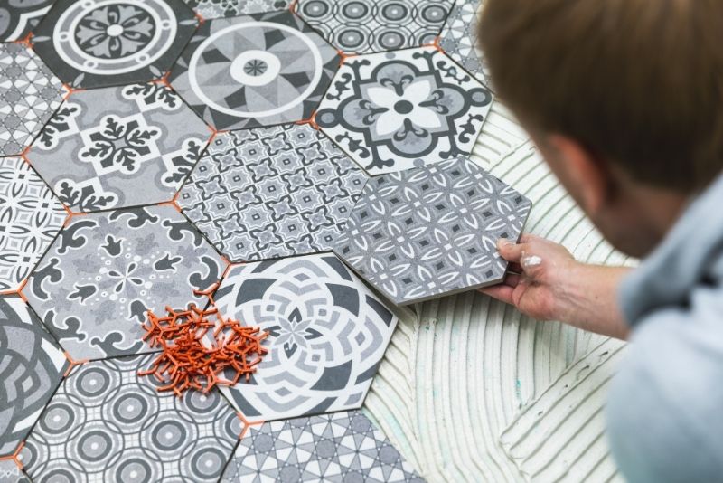 Person installing hexagonal floor tiles for an outdoor patio area