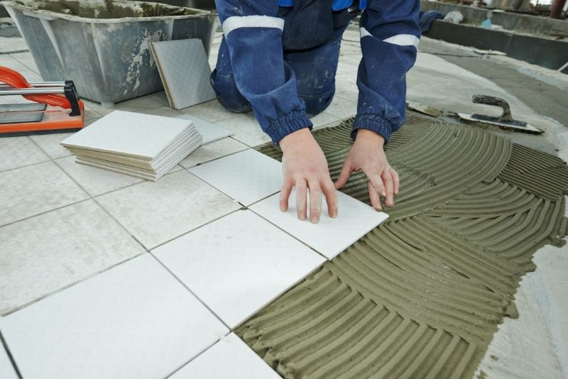 Tiler installing floor ceramic tiles for a kitchen renovation in Port Kembla